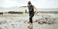 Annalena Baerbock läuft über einen matschigen Strand ohne Schuhe